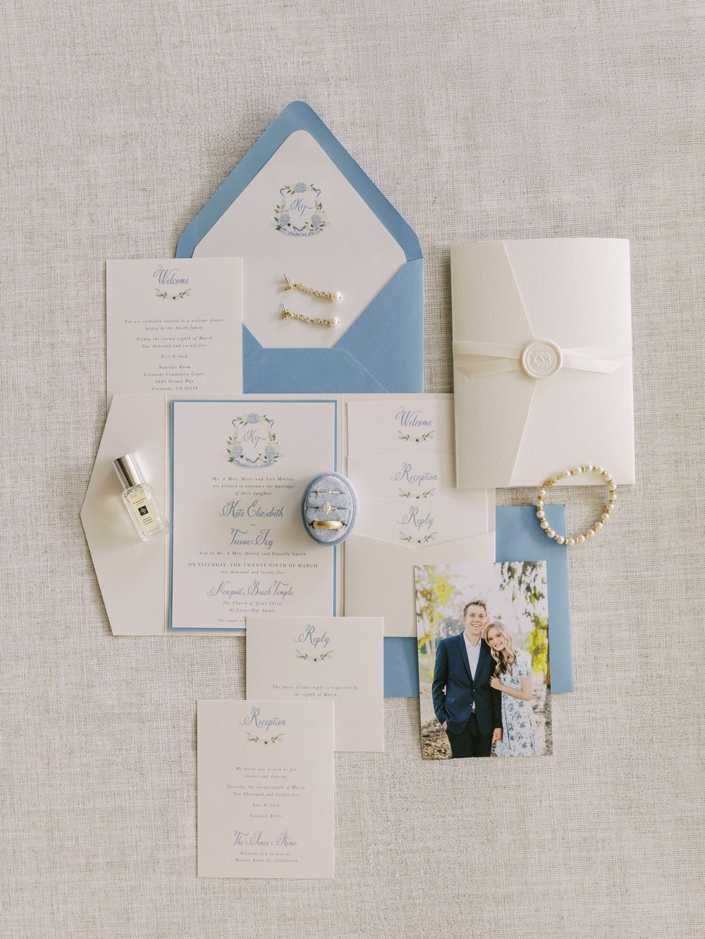 Elegant wedding invitation suite in light blue and white with delicate calligraphy and matching envelopes.
