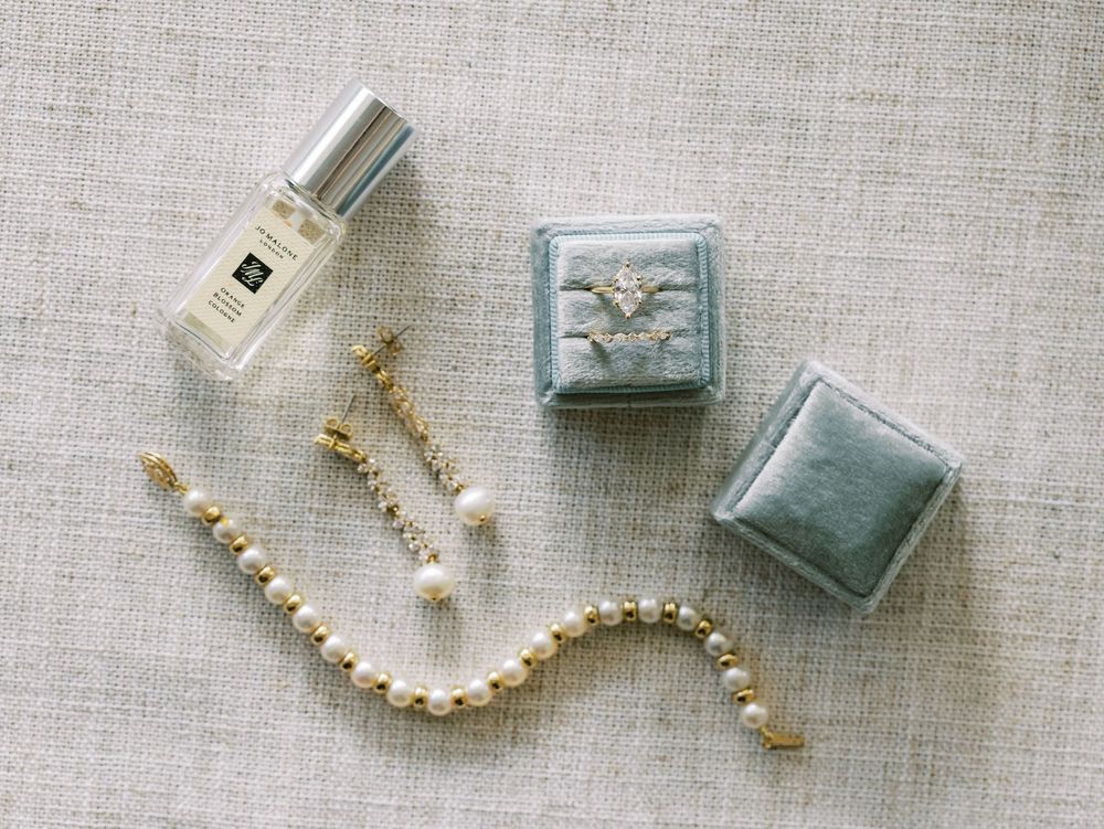 Pearl necklace and earring set displayed with vintage-style blue jewelry boxes on linen fabric.