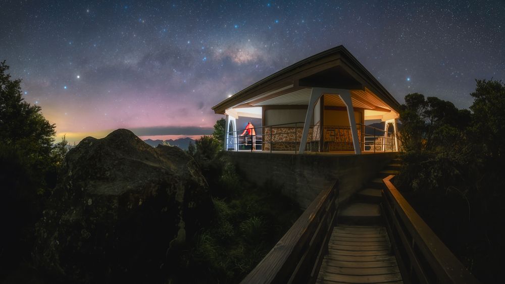 Rustic cabins illuminated at twilight with stars visible in the darkening sky.