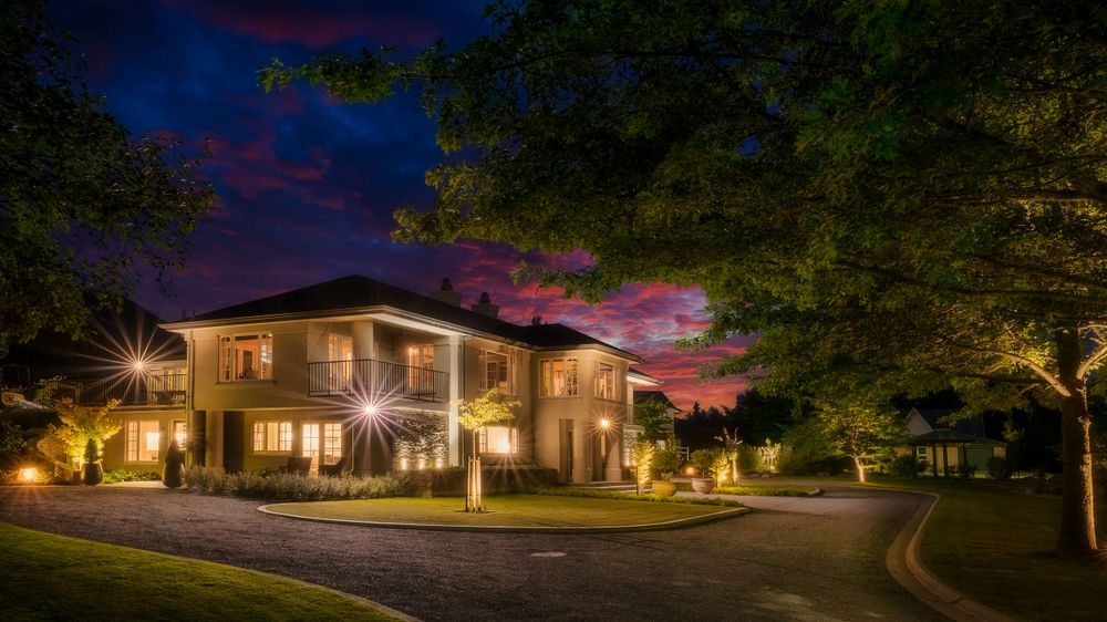 Two-story luxury residence with dramatic lighting under purple evening sky.