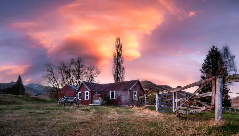 Vibrant sunset sky with pink and orange clouds over a rural landscape.