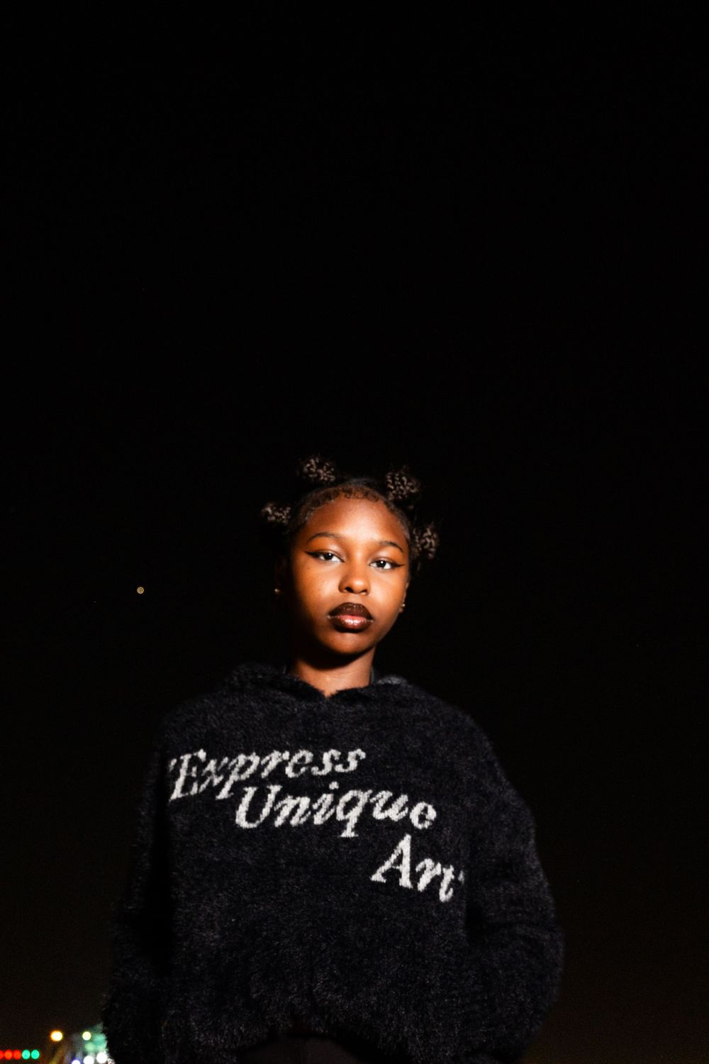 Dramatic nighttime portrait featuring black sweater with 'Express Unique Art' lettering.