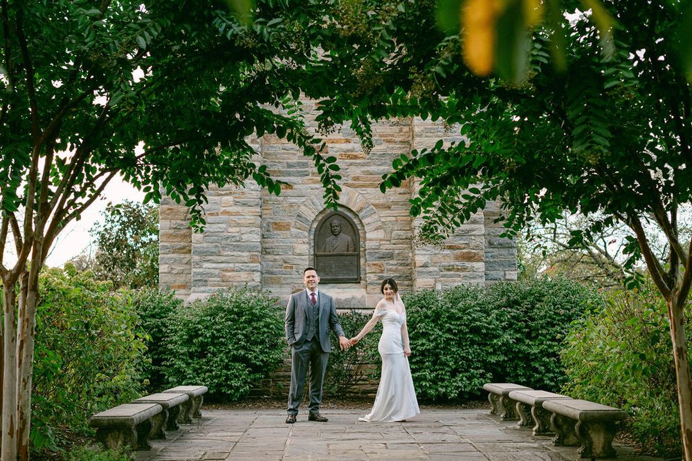 Wedding ceremony setup with stone walls and trees creating a natural outdoor aisle.