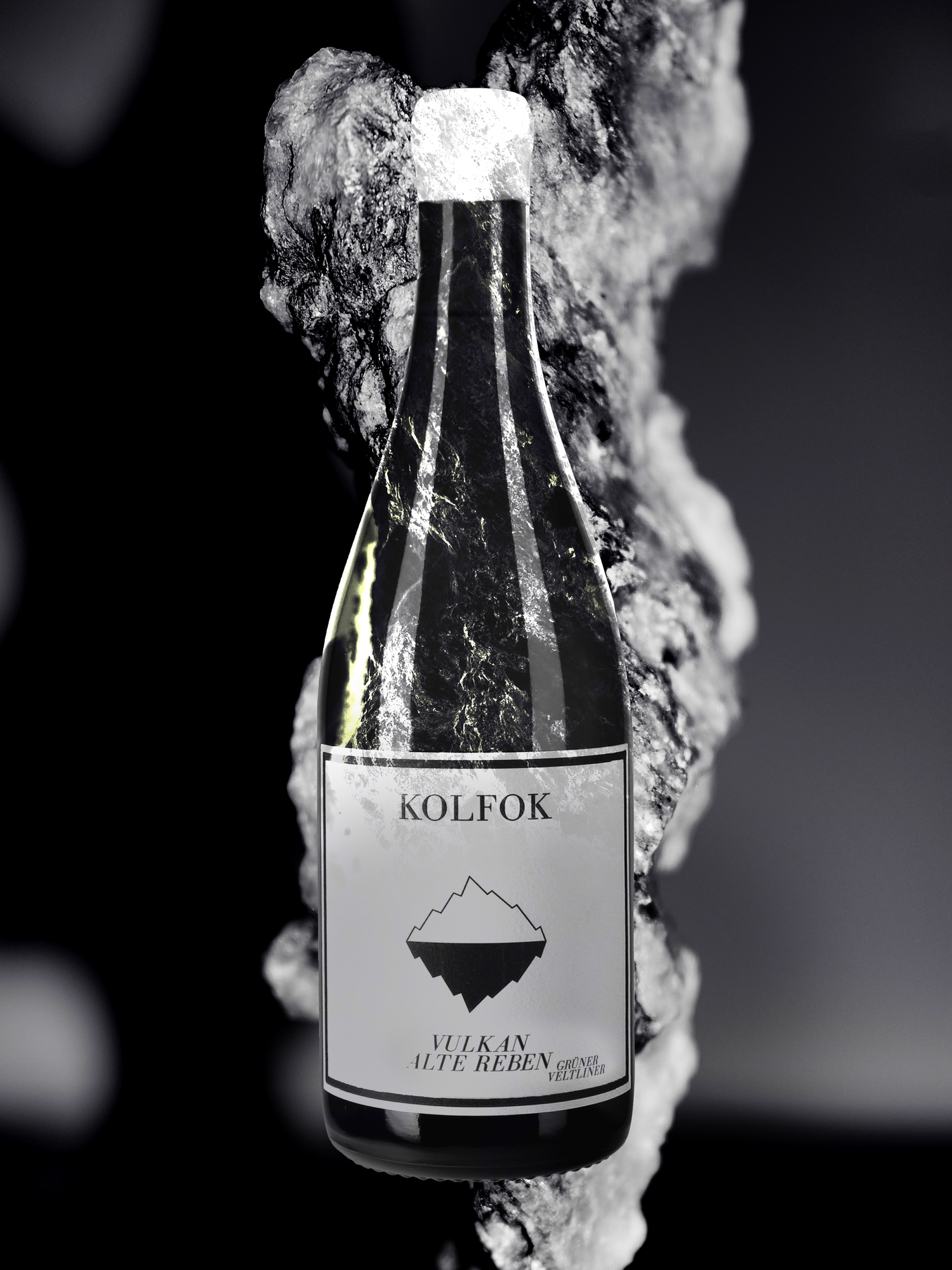 Kolfok Vulkan Alte Reben wine bottle dramatically emerging from volcanic rock formation.