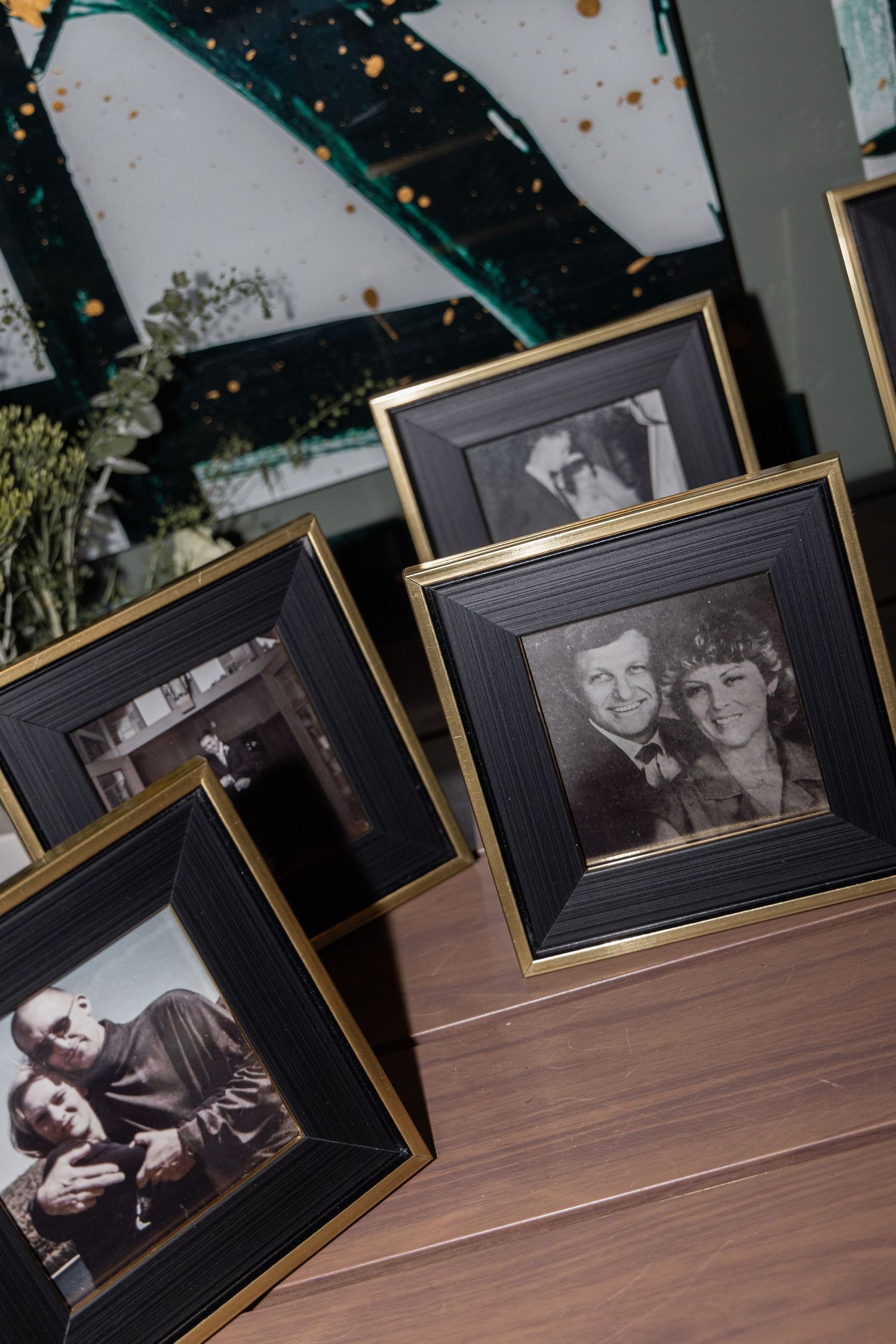 A row of black and white framed photographs displayed on a wooden surface with soft lighting.
