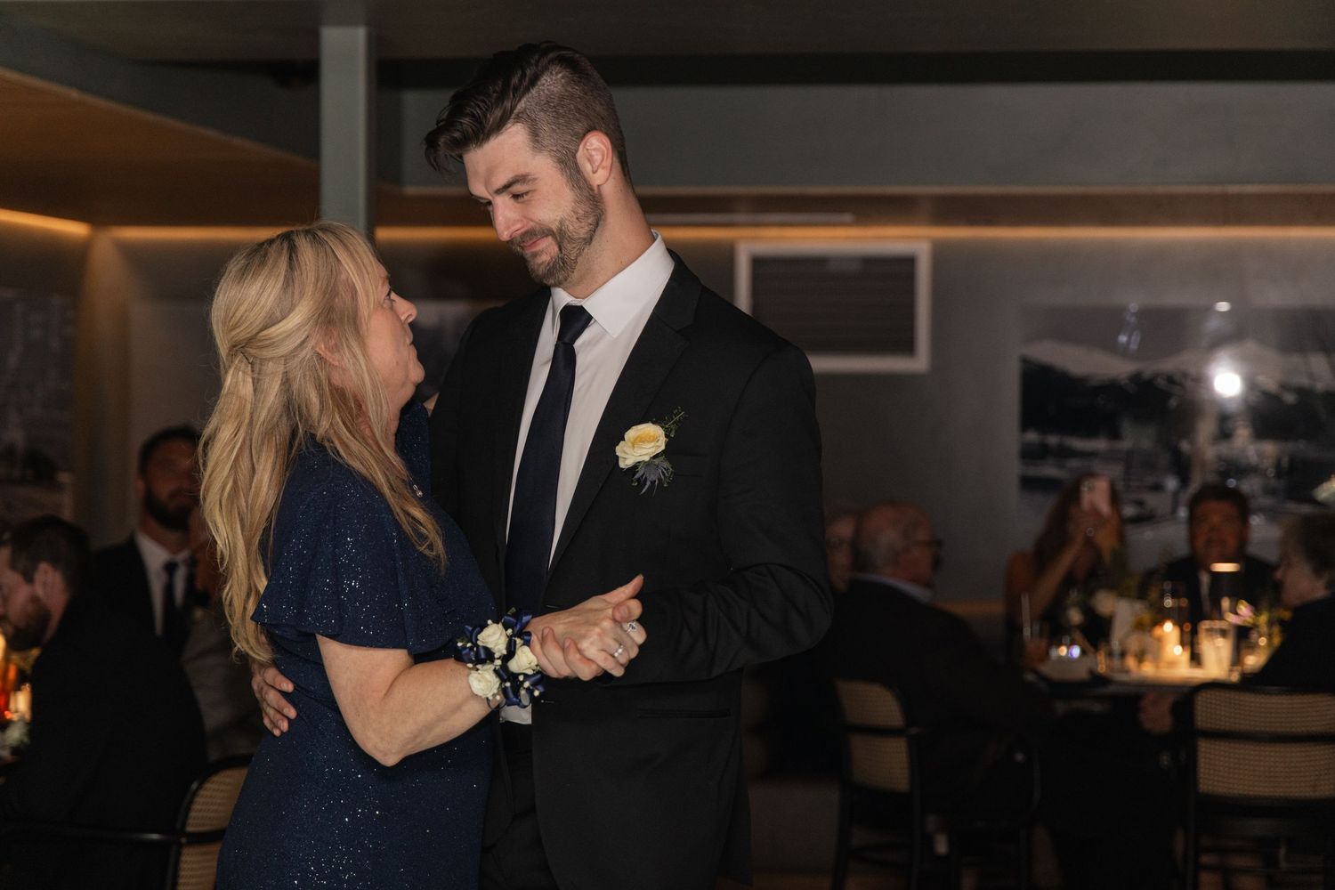 Wedding reception guests mingle and celebrate in an elegantly lit indoor venue.