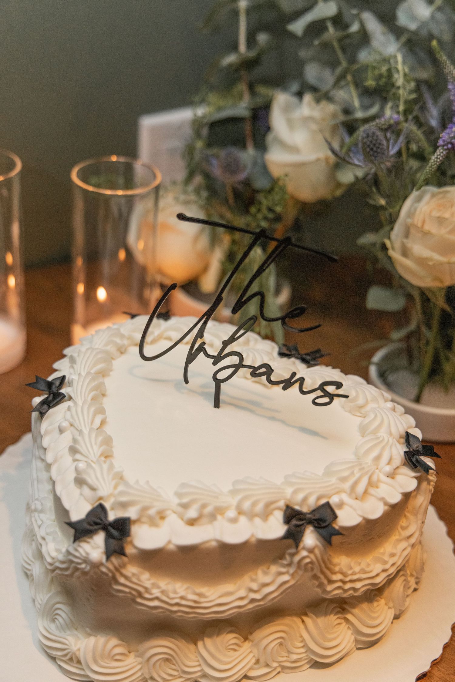 Heart-shaped white wedding cake with delicate piped frosting and black bow decorations.