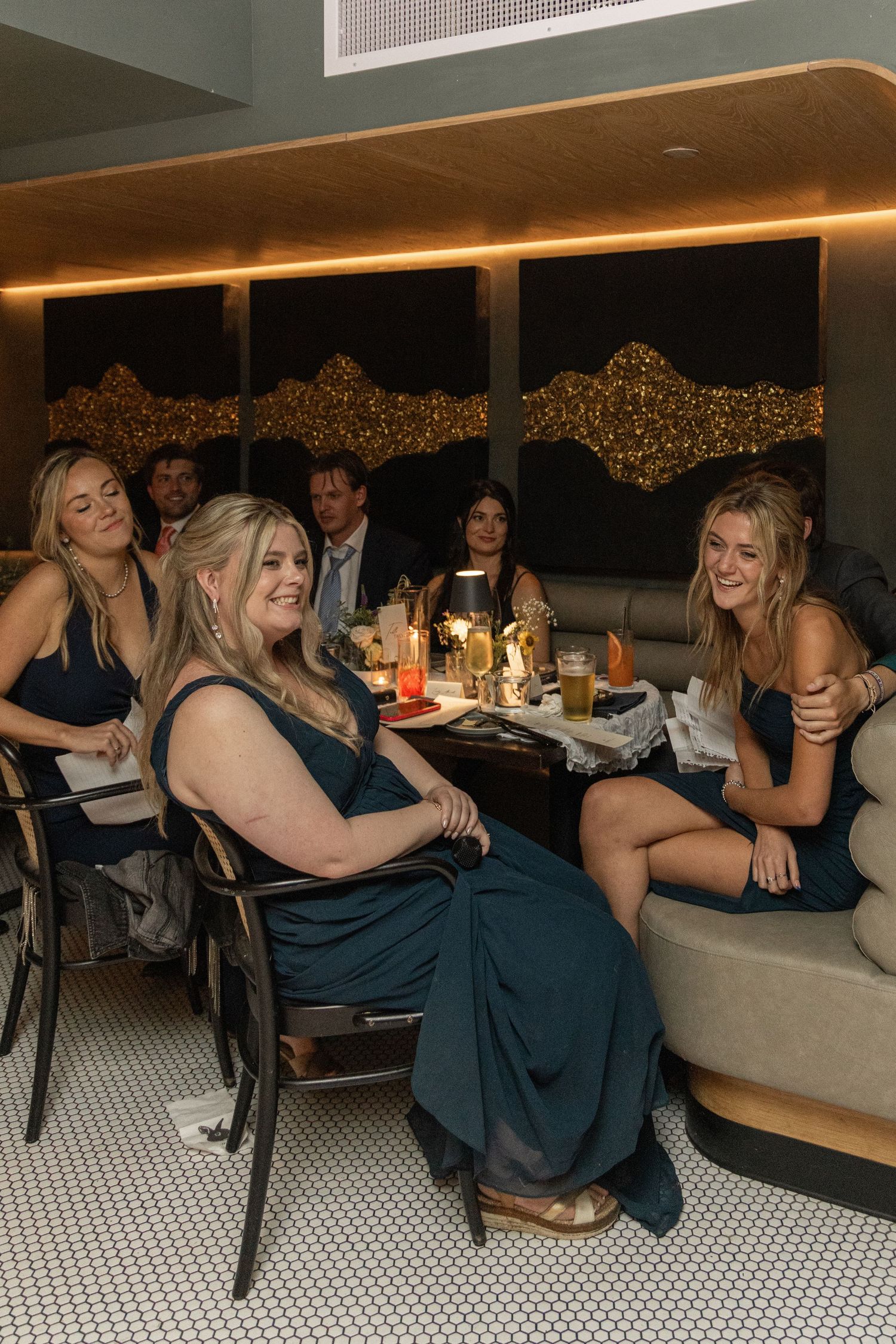 Group of wedding guests in navy blue dresses enjoying a casual moment together at a reception.