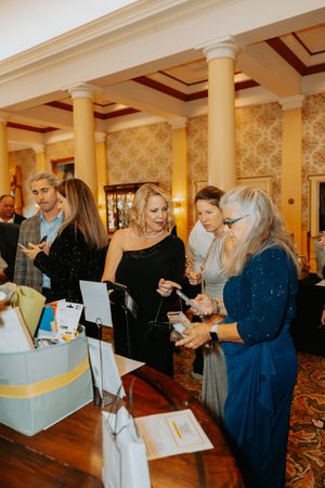 Guests browse items at an indoor event with classical columns and warm lighting.