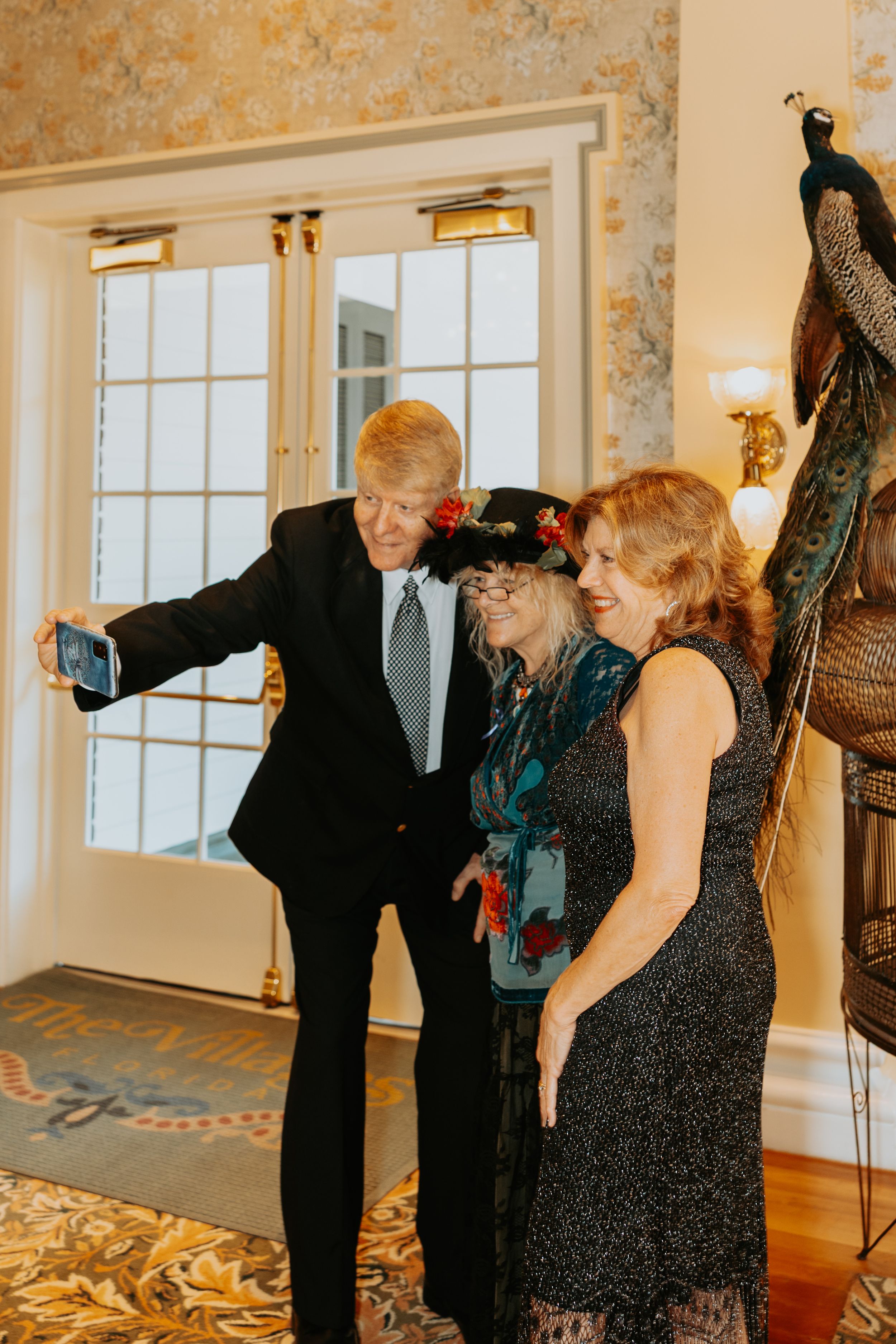 Elegantly dressed couples dancing together at a formal event in a bright ballroom with ornate decor.