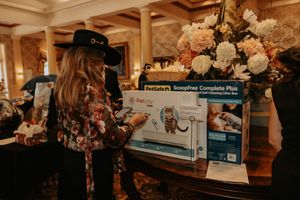 Person in floral attire examines a boxed product display at an elegant event setting.