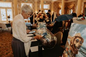 People browsing items displayed on tables at an elegant indoor venue.