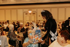Crowded formal event with attendees gathered around decorated tables.