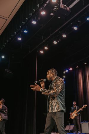 Stage performers entertain an audience under dramatic lighting at a concert venue.