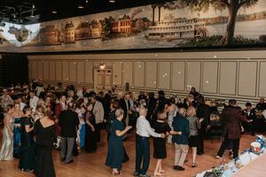 People dancing in pairs across a large ballroom floor during a social dance event.
