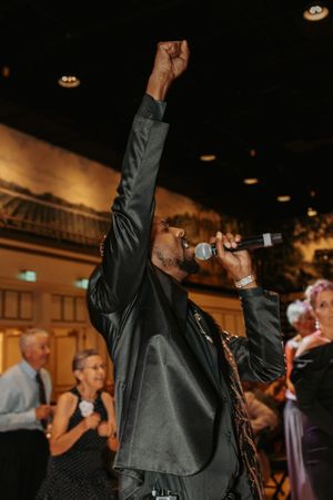 People dancing enthusiastically with raised arms at a dimly lit evening celebration.