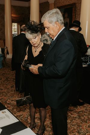 Attendees in formal attire reviewing materials at a carpeted event venue.