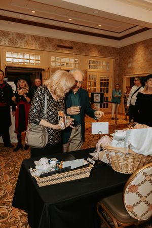Silent auction display tables with gift baskets and items arranged on black tablecloths.