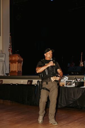 Security personnel in tan uniforms monitoring an event space with equipment.