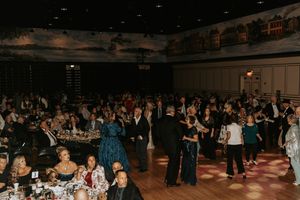 Panoramic view of a crowded dance hall event with people gathered on the dance floor under dim lighting.
