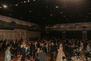 Large crowd gathered in a dimly lit venue space for an indoor event.