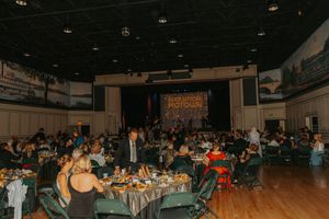 Wide shot of an indoor venue with audience members seated at tables during an event.