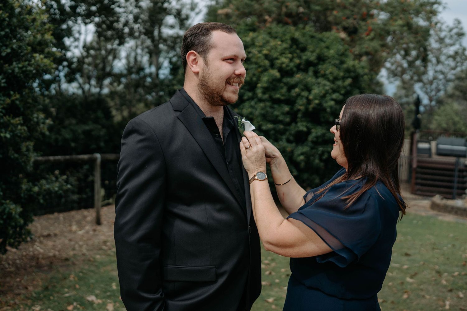 A couple embraces outdoors in a romantic photoshoot with natural greenery in the background.