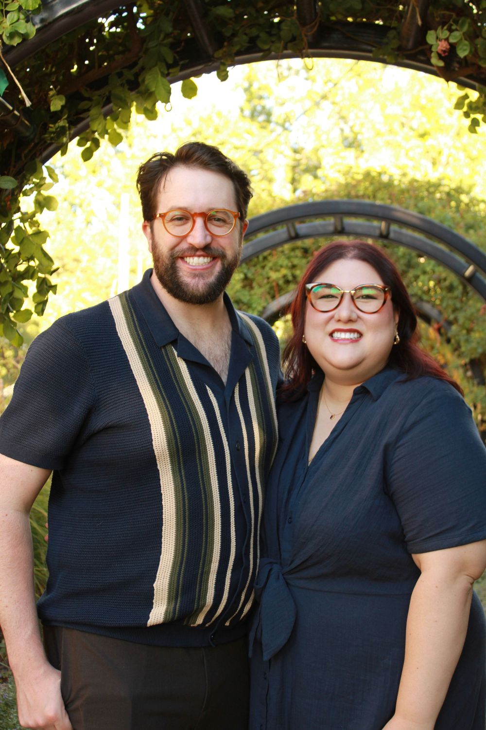 Couple in navy blue outfits smiling together during outdoor photo session.