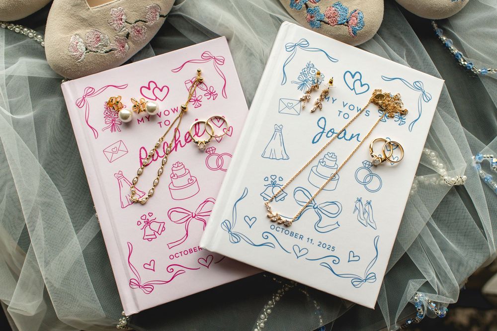 Pink and blue hardcover books with delicate gold jewelry pieces displayed on their covers against tulle fabric background.
