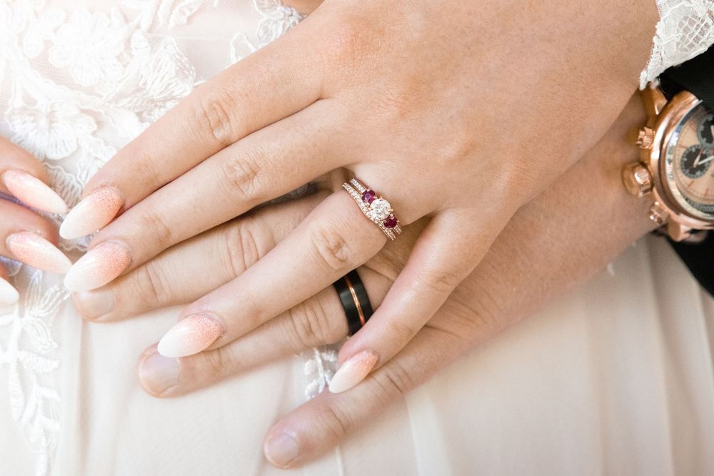 Close-up view of hands displaying engagement rings and wedding bands in various poses against a light background.
