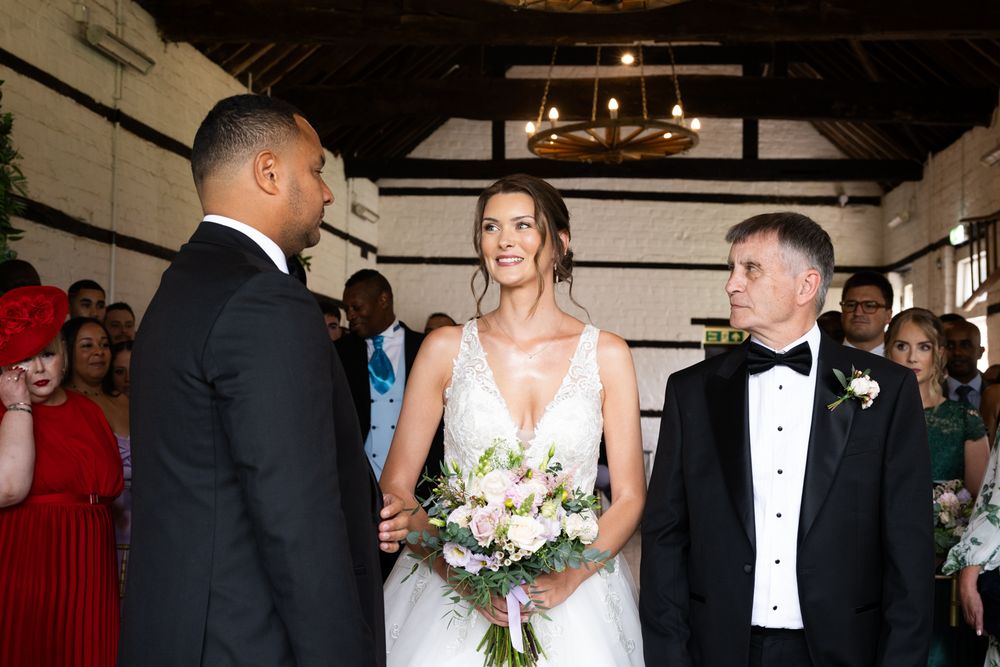 Wedding ceremony scene in a rustic venue with exposed wooden beams and elegant decor.
