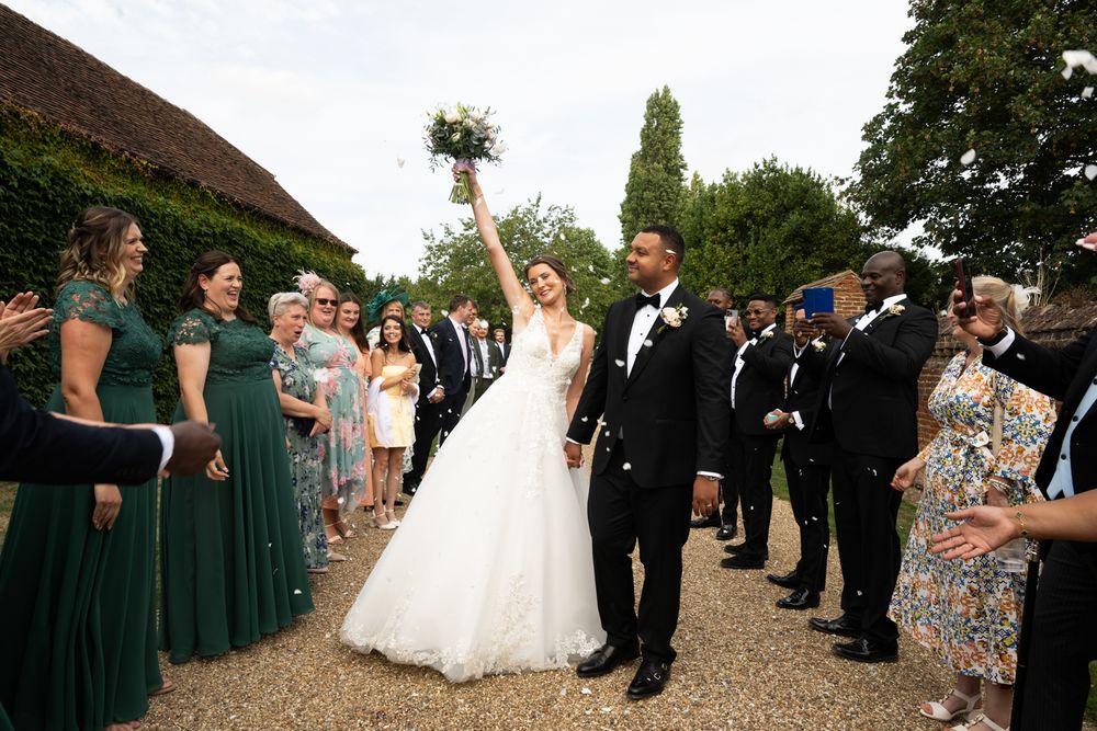 Wedding party and guests gathered outdoors for celebration with bridesmaids in dark green dresses.