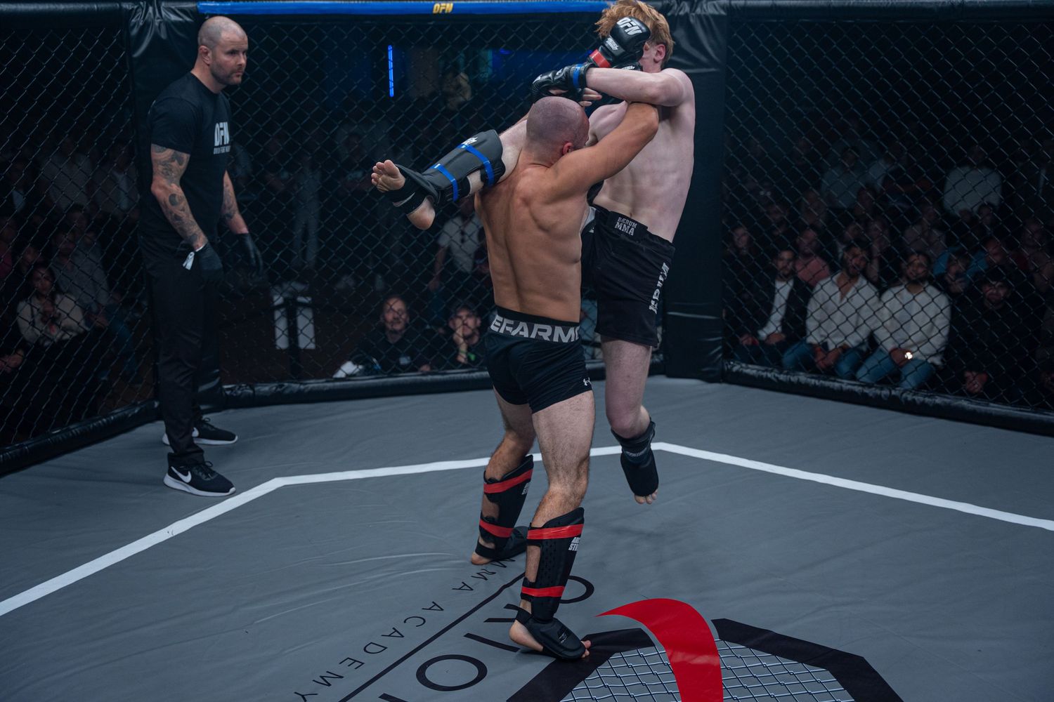 MMA fighters engage in a ground grappling exchange during an intense octagon match.
