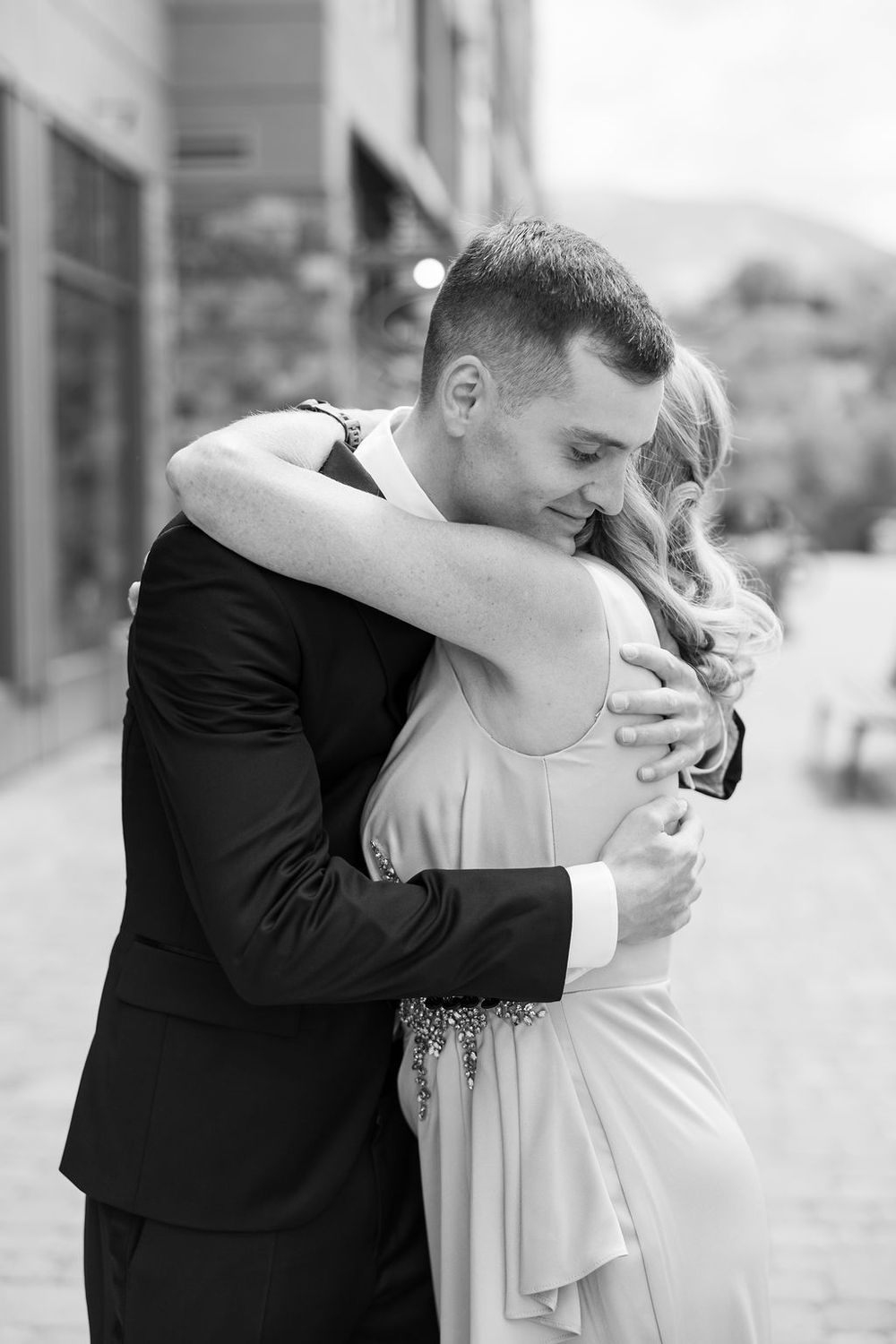 Black and white photo of intimate embrace between newlyweds in formal wedding attire.