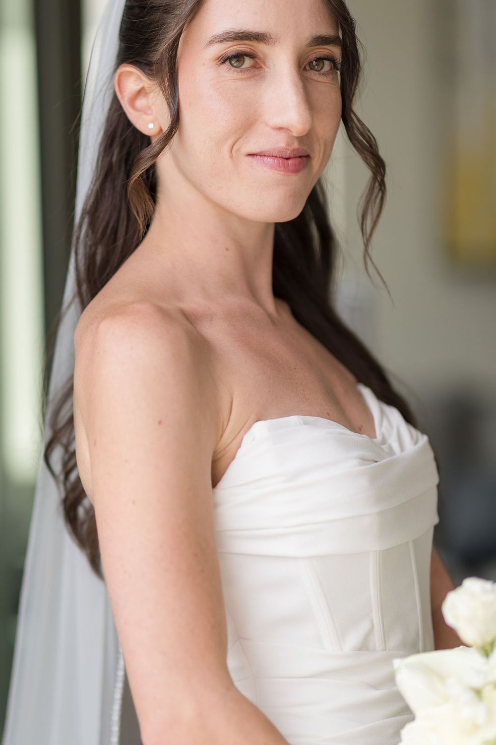 Elegant bride wearing a white strapless wedding gown with sweetheart neckline and flowing veil.