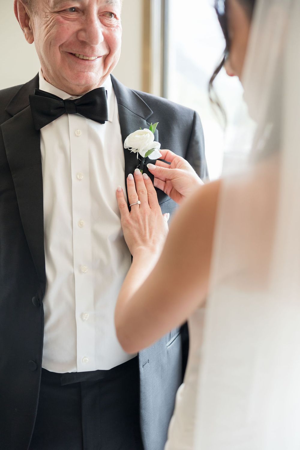 A close-up moment shows a boutonniere being pinned to a formal tuxedo lapel during wedding preparations.