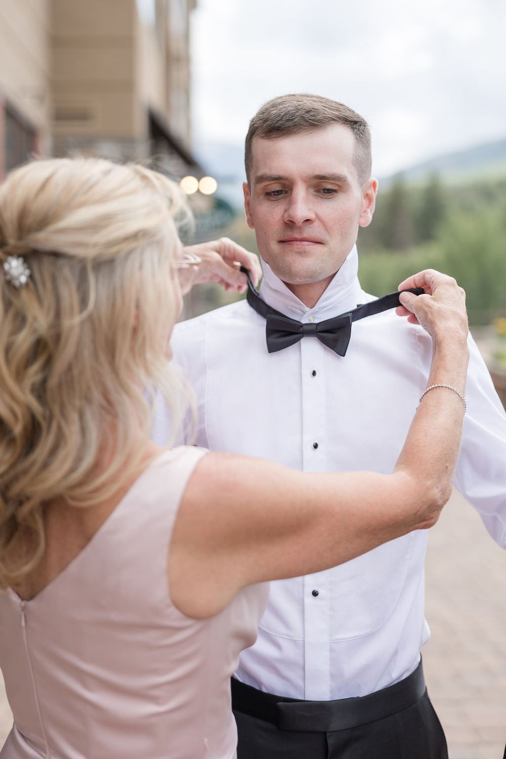 A sequence of shots showing someone adjusting a black bowtie on a formal white dress shirt.