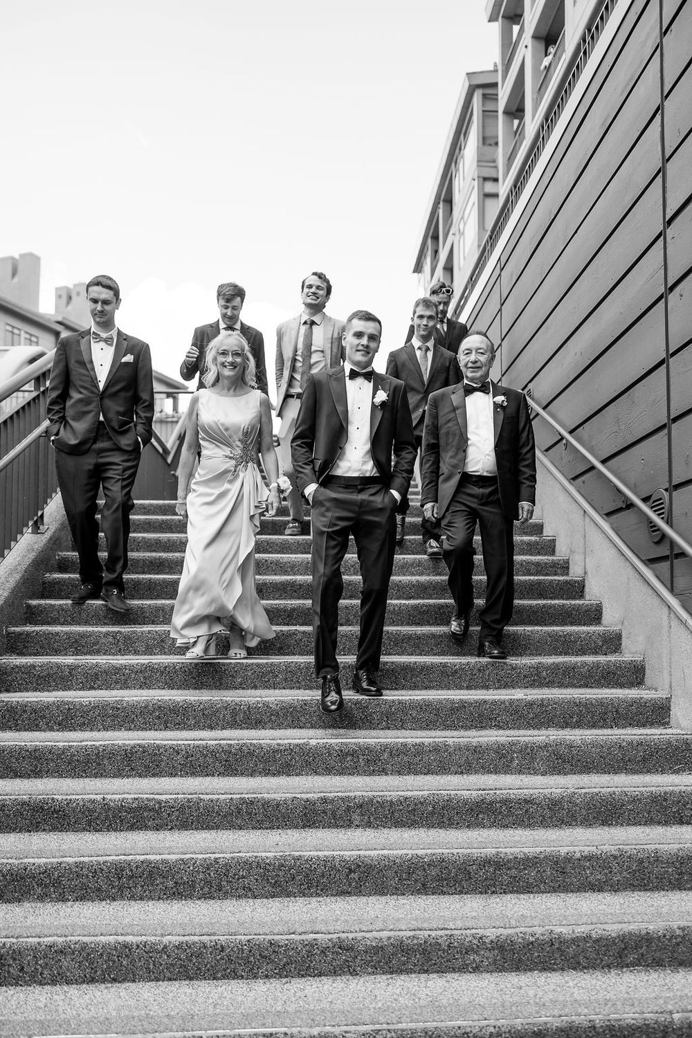 Wedding party poses playfully on concrete steps in progressive black and white sequence.