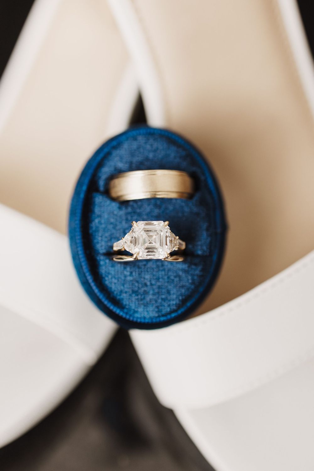 Wedding rings displayed on a navy blue velvet ring box with white background showing multiple angles and details.