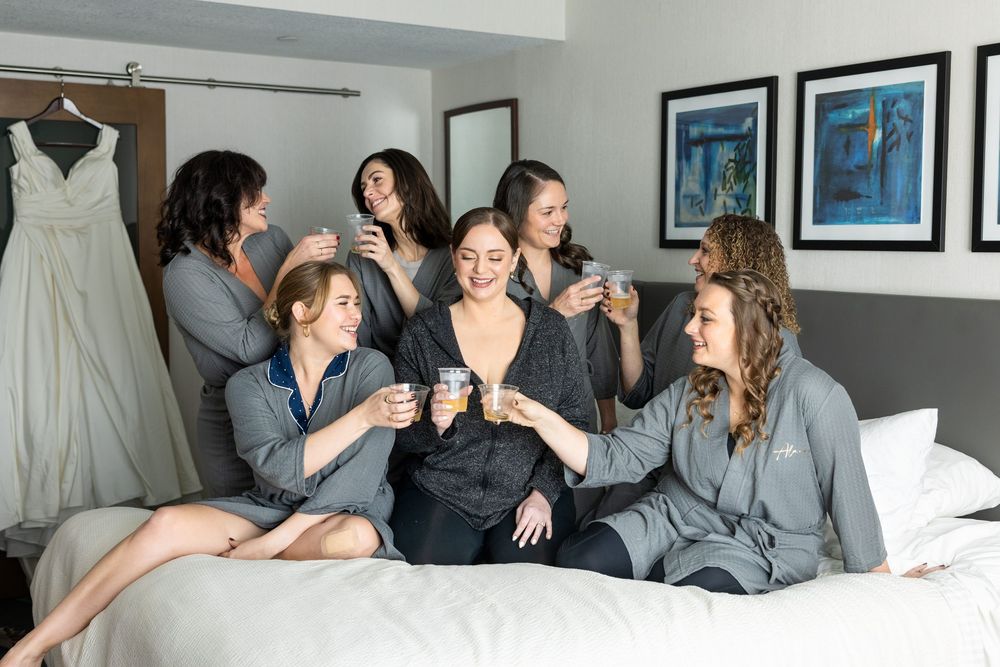 A group of people wearing matching gray robes lounging together on a bed in a casual setting.