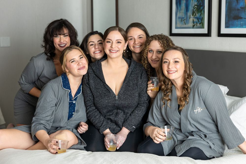 People in coordinated gray robes gather together on a bed for a casual group photo.