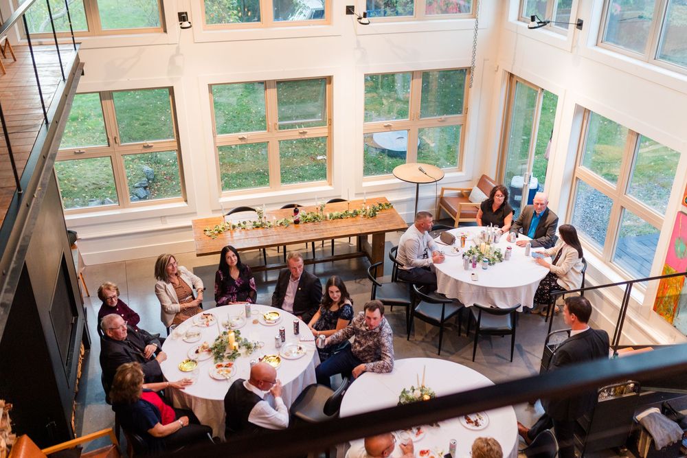 Guests seated at round tables in a bright sunlit room with large windows during a formal dining event.