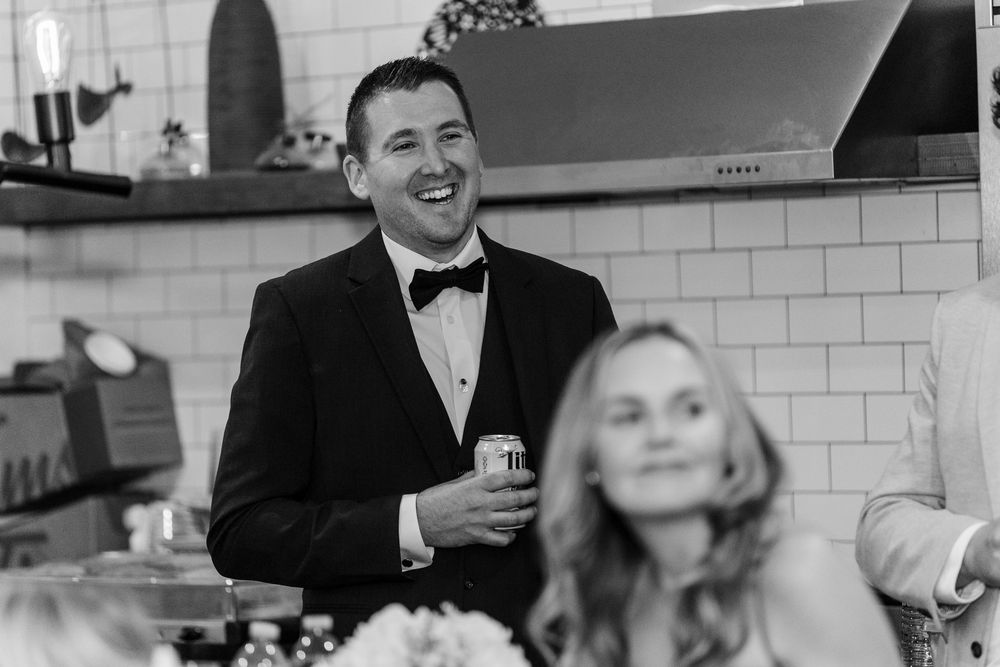 A black and white photo showing guests laughing and enjoying themselves at a formal event.