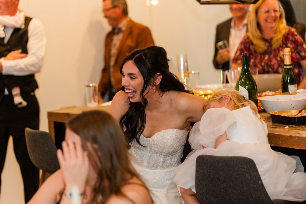 Wedding guests laugh and smile during an emotional reception speech at an elegant indoor venue.