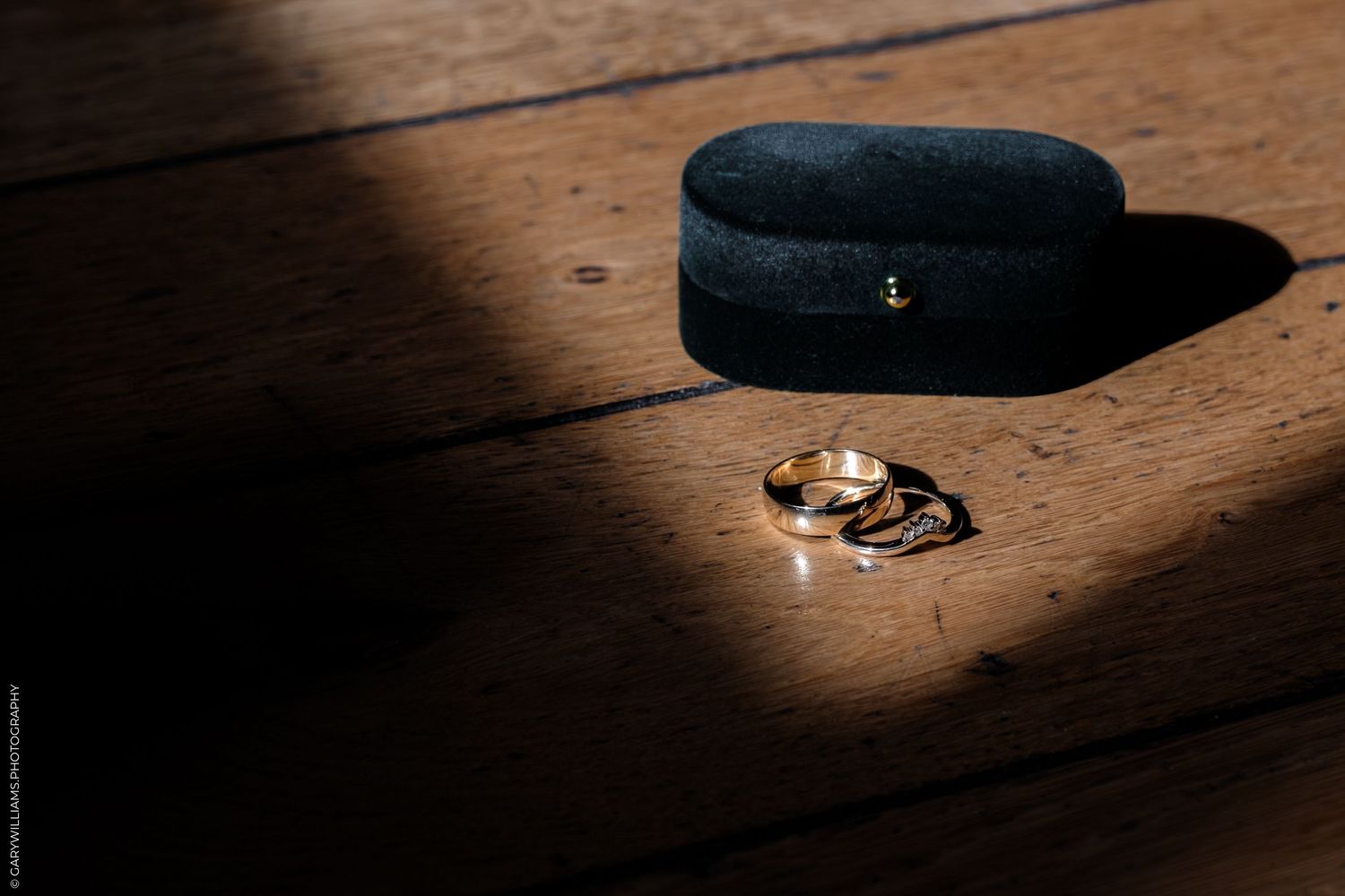A black beret hat sits on a wooden surface illuminated by dramatic lighting from above.