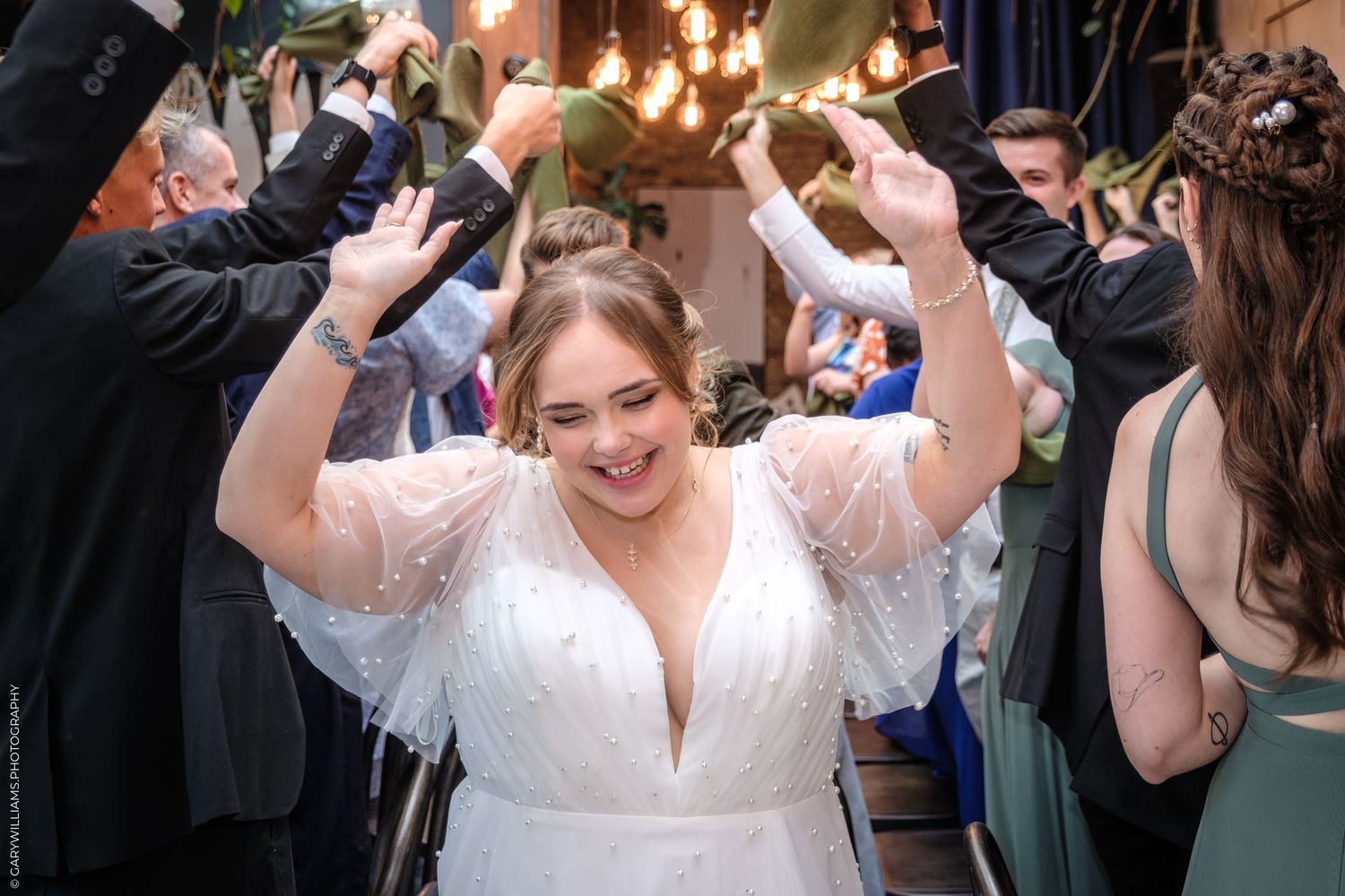 Wedding guests dance and celebrate on a crowded dance floor during a lively reception party.