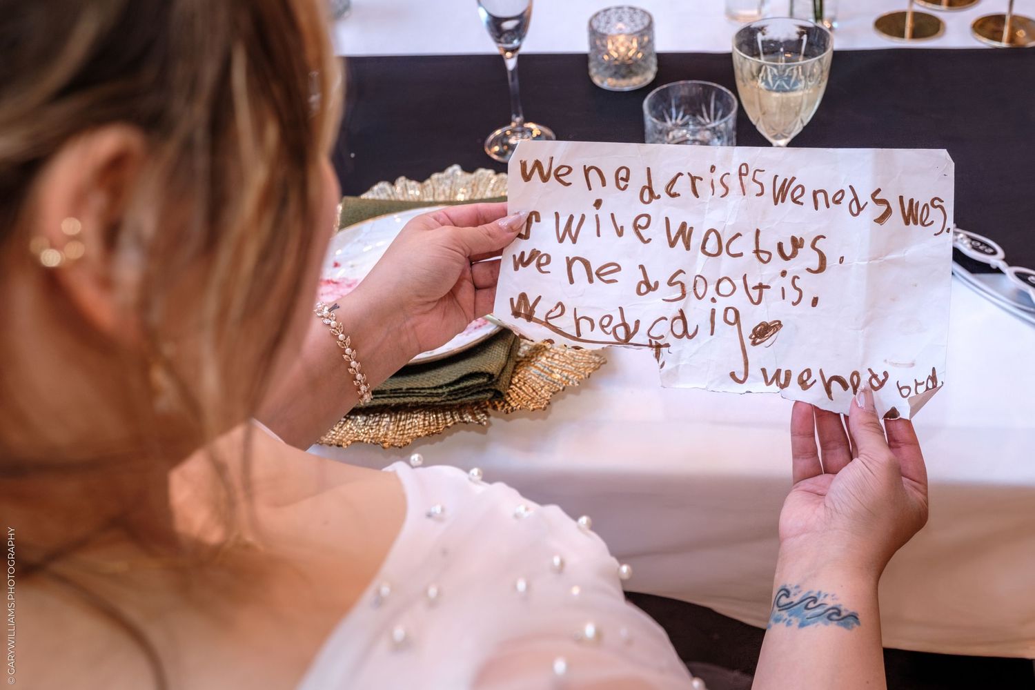 Someone holds up a handwritten sign with text on white paper in front of a dark background.