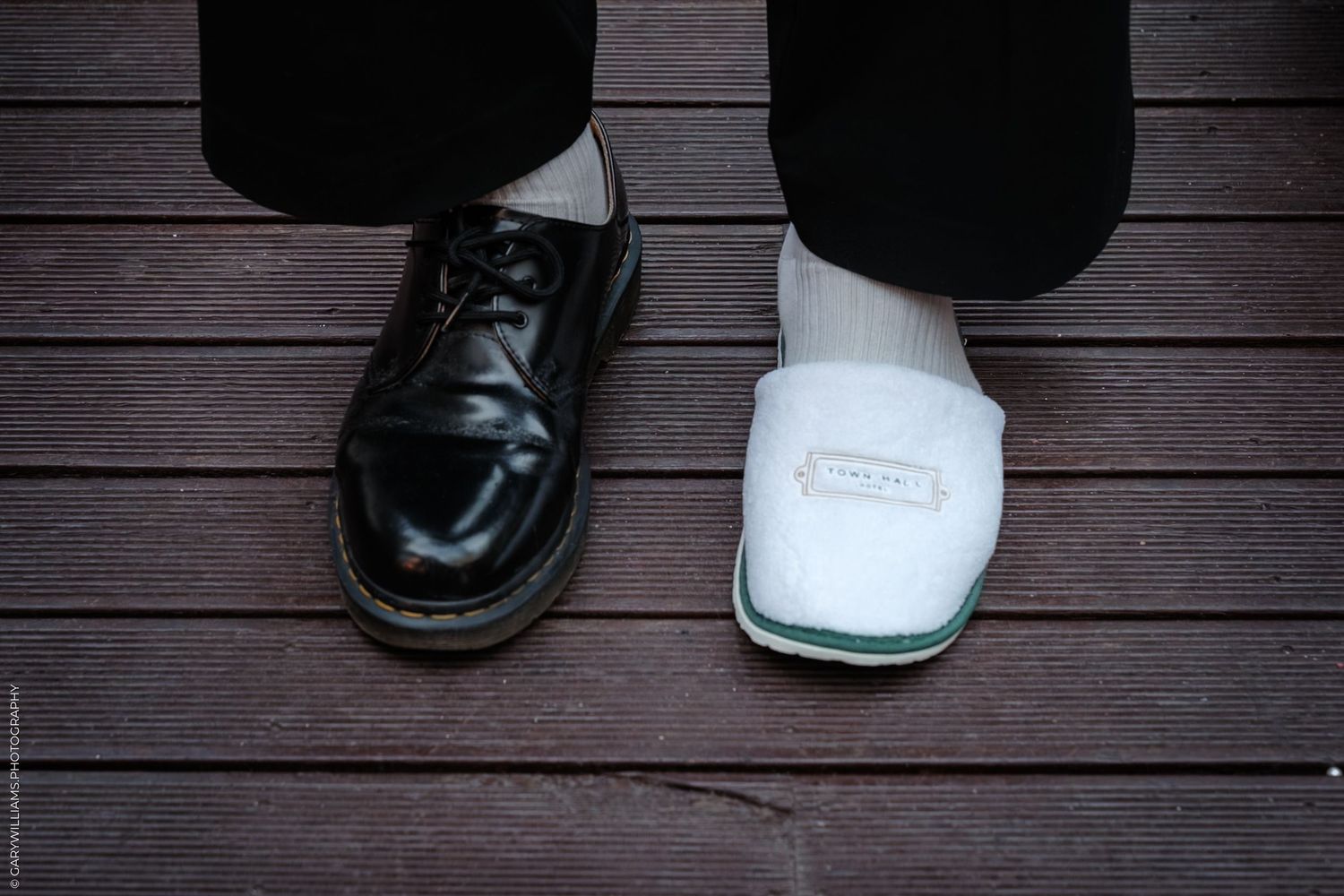 Two pairs of black and white shoes stand on a dark wooden deck surface.