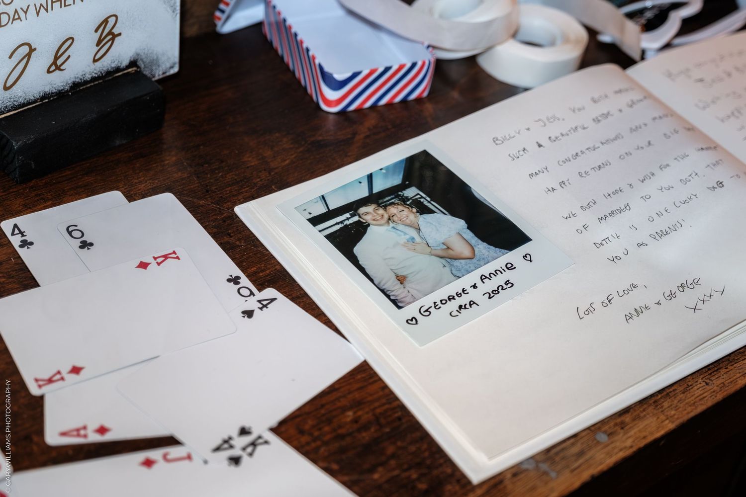 Scattered playing cards and photographs on a rustic wooden table surface create a nostalgic memory display.