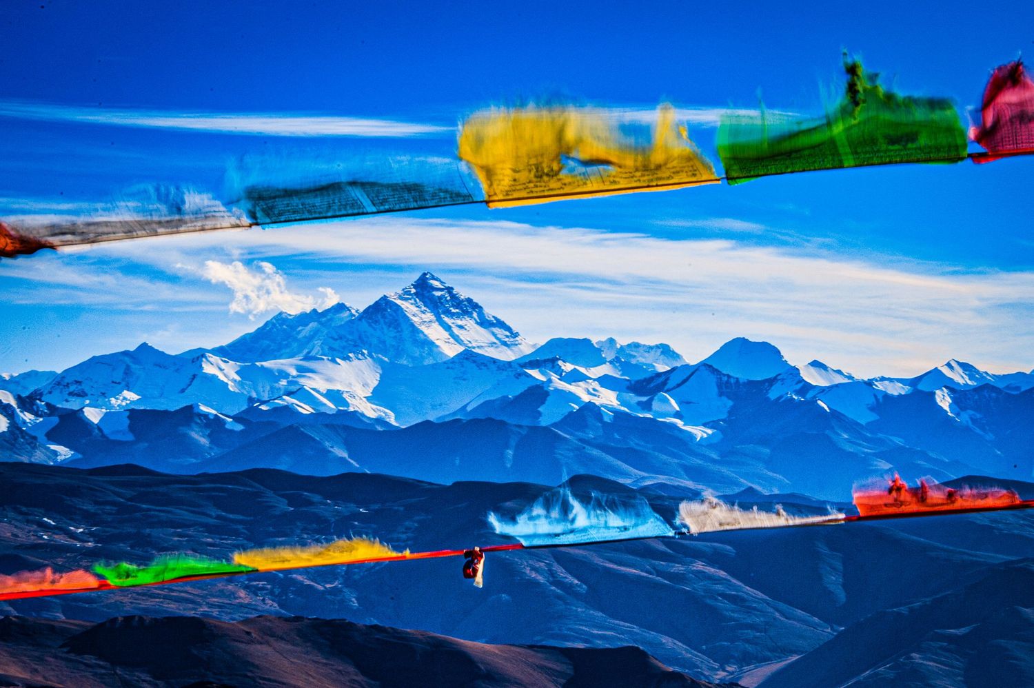 Panoramic view of snow-capped mountains against a bright blue sky with colorful kayaks in the foreground.